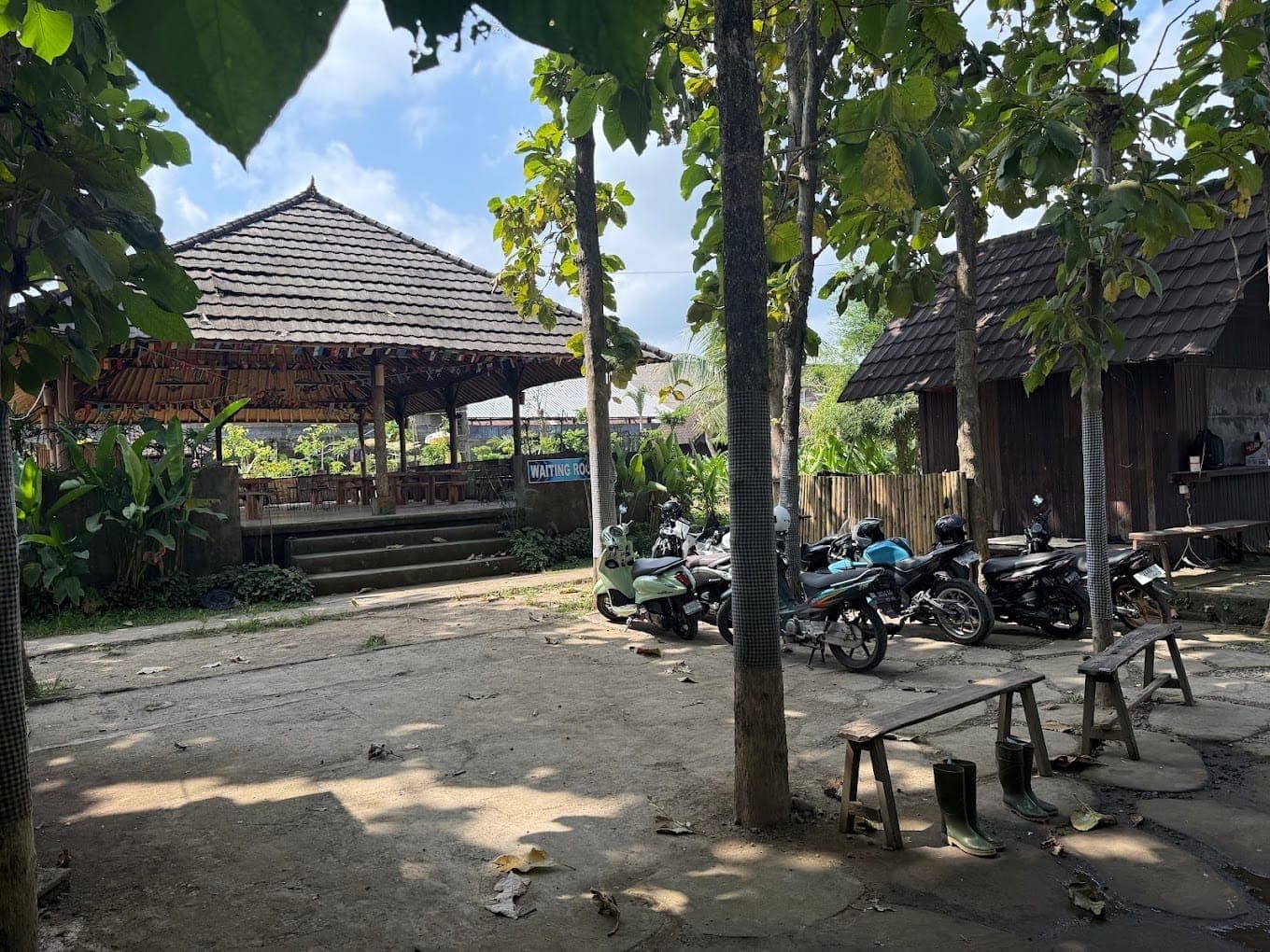 The open pavilion at the ATV base, with parked bikes and boots lined up in the yard