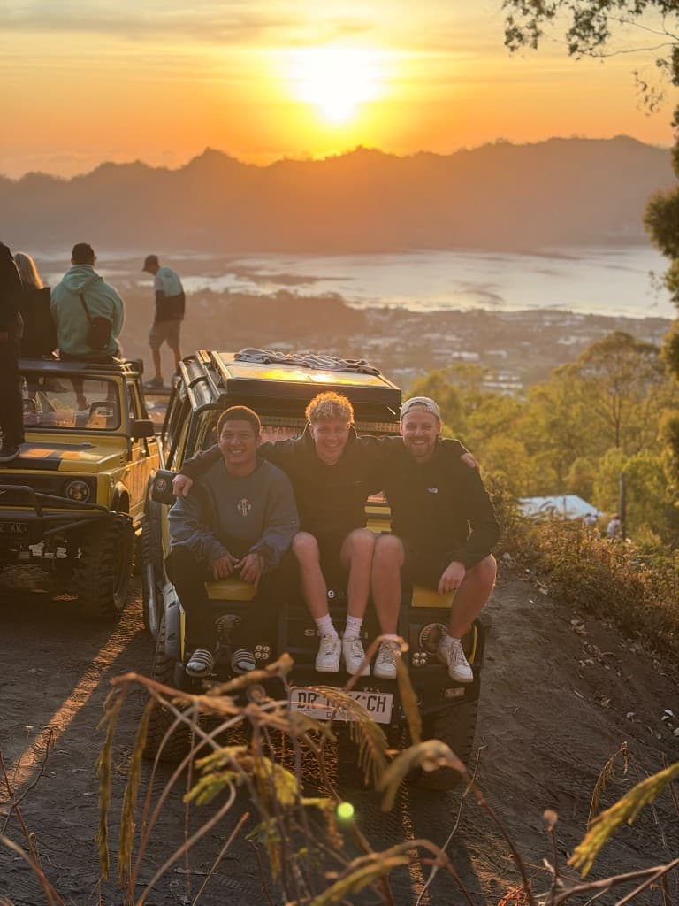Three people on a yellow jeep above Lake Batur