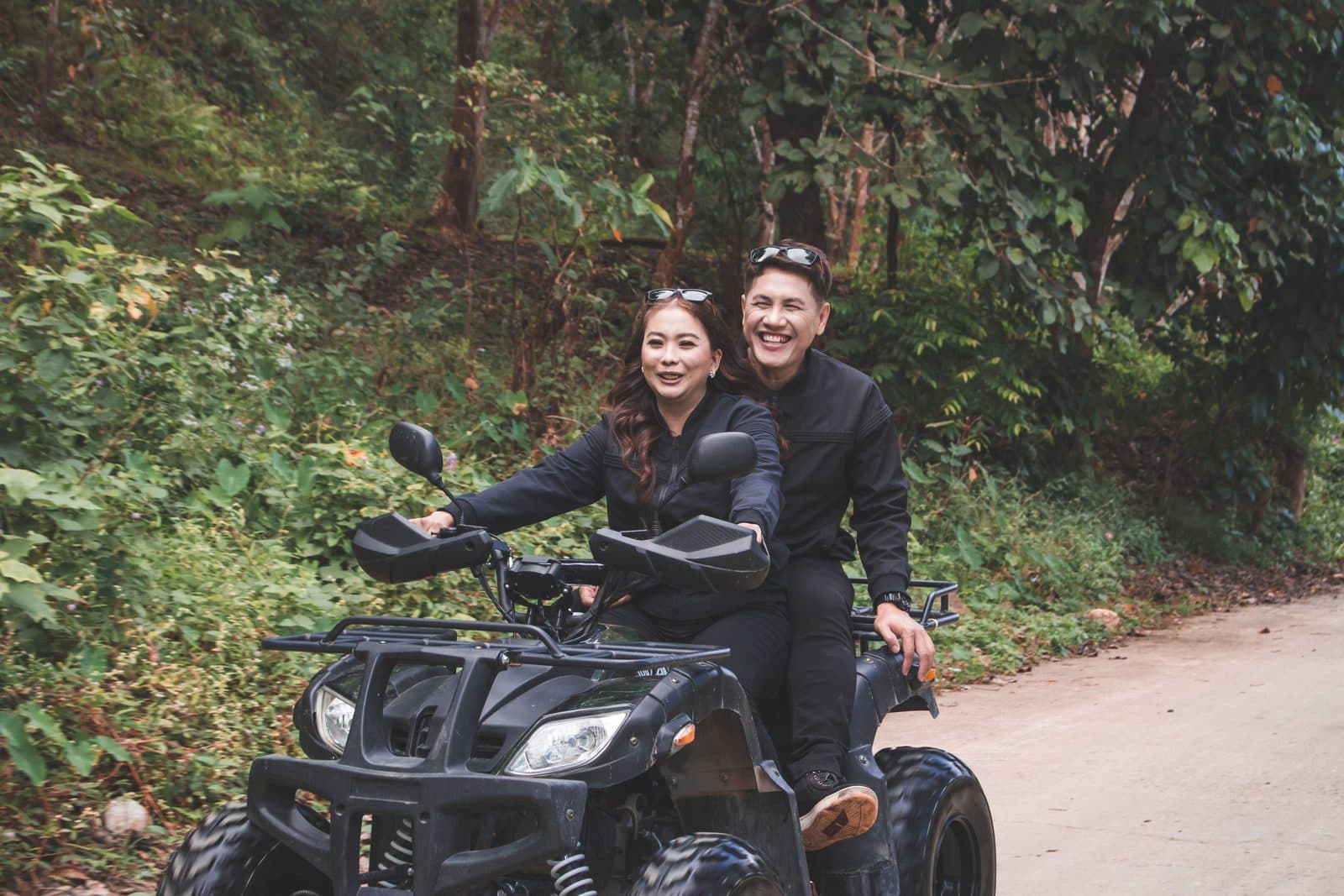 A couple sharing one black quad on the jungle road at Sedang